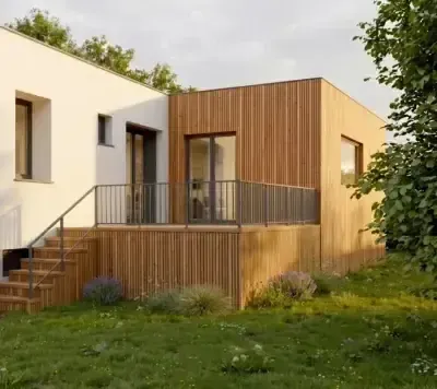 Extension à ossature bois Greenkub accolée à une maison enduite claire, bardage bois vertical et terrasse surélevée ouverte sur le jardin