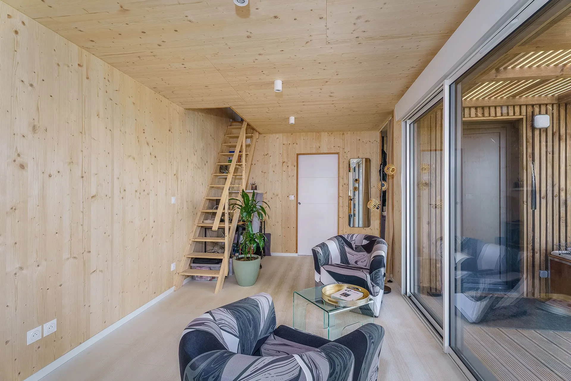 GK50 Allier · espace de vie avec accès mezzanine, structure bois massif apparente et terrasse extérieure