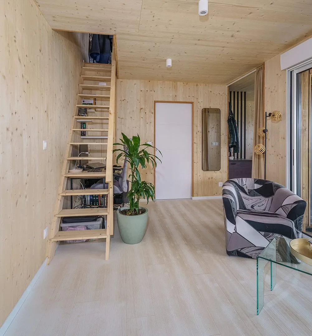 Intérieur maison 50m² avec mezzanine · murs bois massif, escalier en bois clair, lumière naturelle