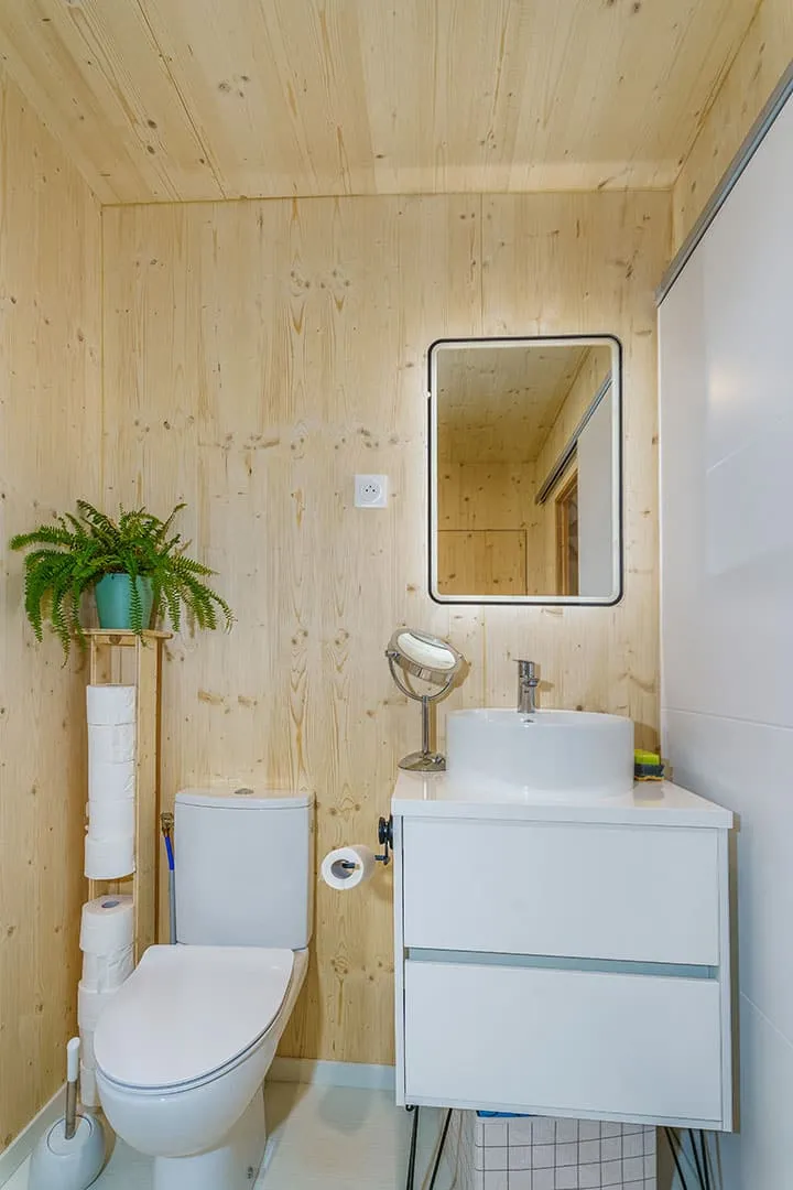 Salle d’eau maison bois Greenkub · vasque blanche, WC, miroir LED, murs bois massif épicéa naturel