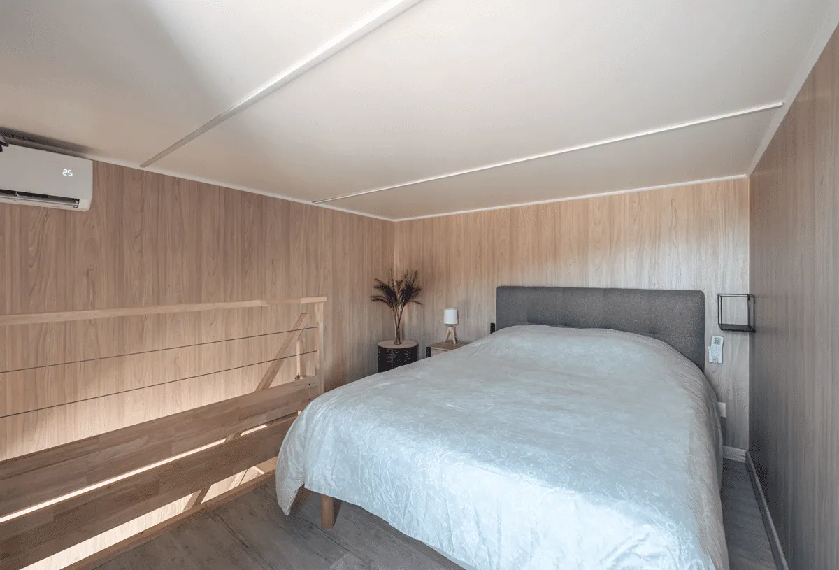 Une chambre sur la mezzanine d’une construction bois