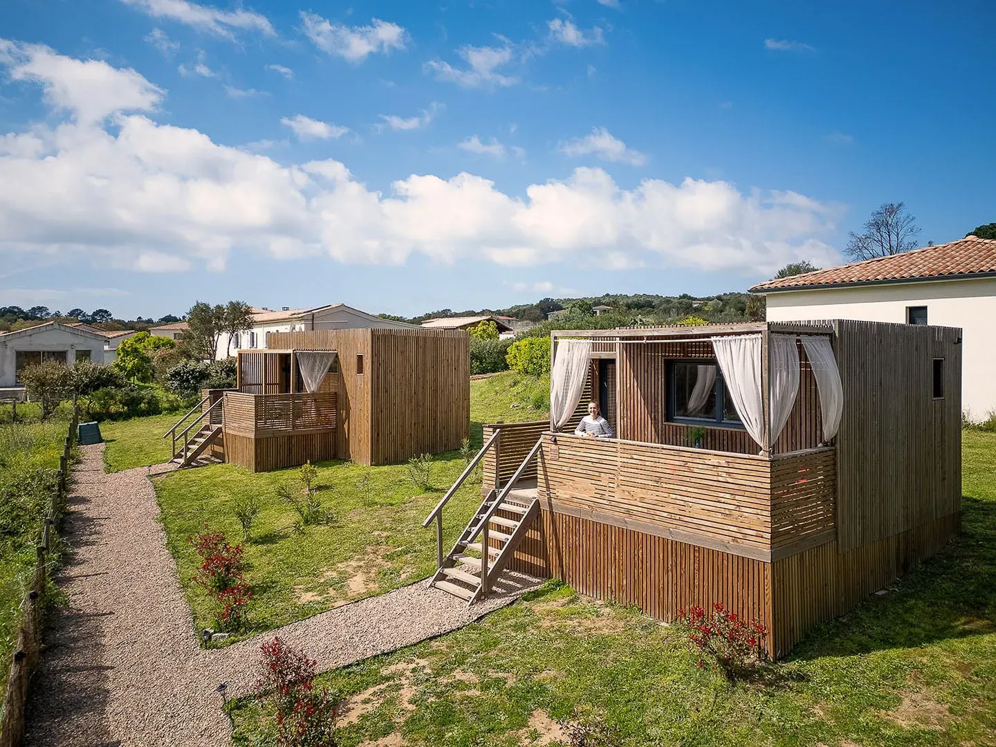 Deux studios Greenkub GK20 installés sur un terrain en pente végétalisé, bardage bois et rideaux blancs