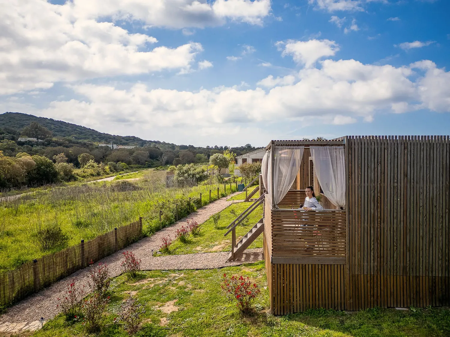 Studio de jardin Greenkub GK20 en bois naturel avec terrasse à claire-voie et escalier d’accès, vue extérieure ensoleillée