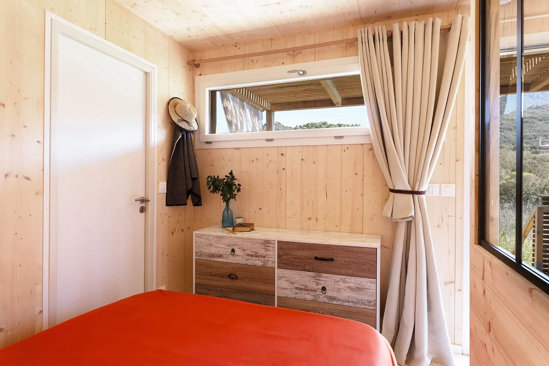 Chambre d’un studio Greenkub GK20 avec lit double, linge de lit rouge corail