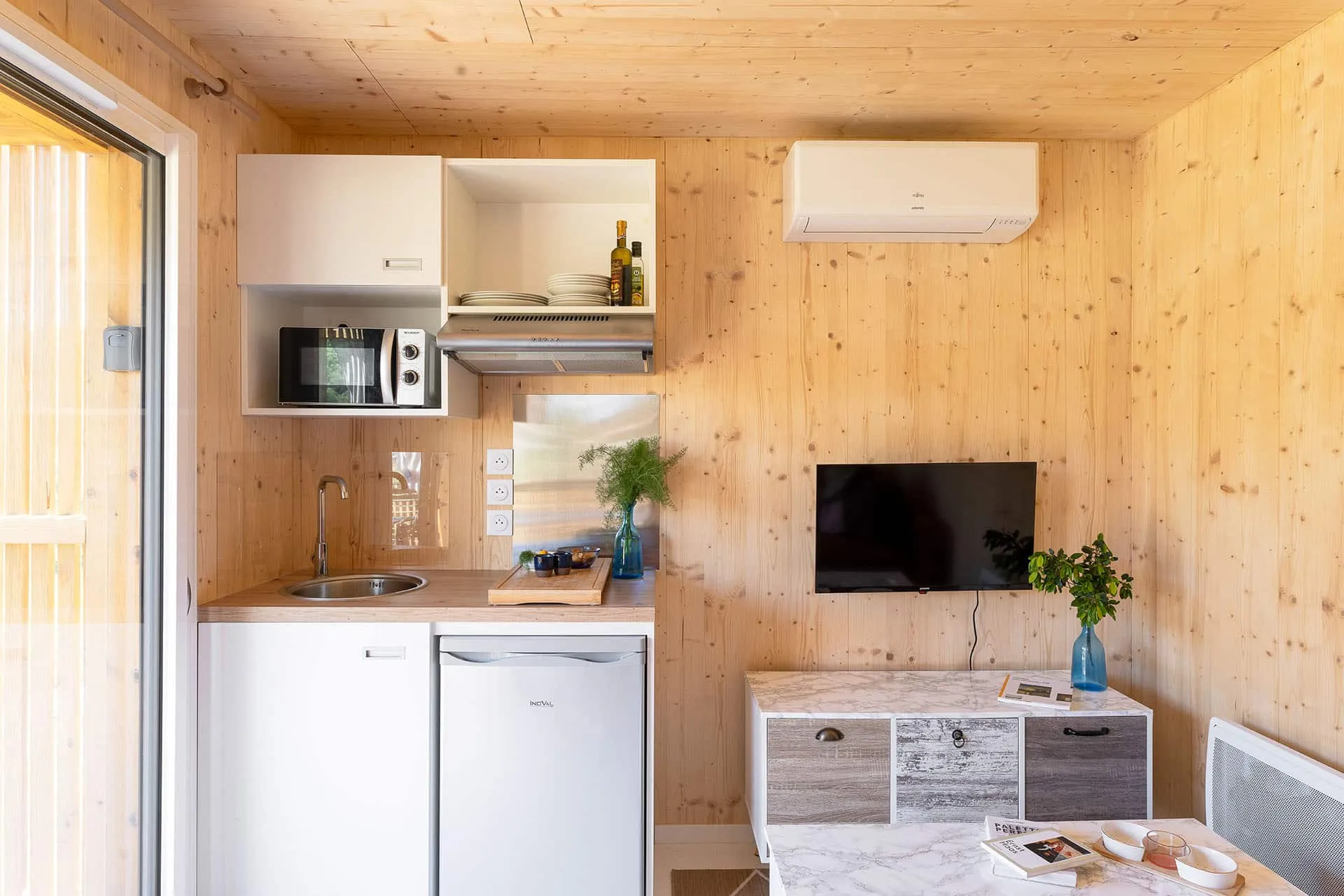 Détail cuisine d’un Greenkub GK20 : hotte aspirante, micro-ondes encastré et plan de travail bois avec évier rond