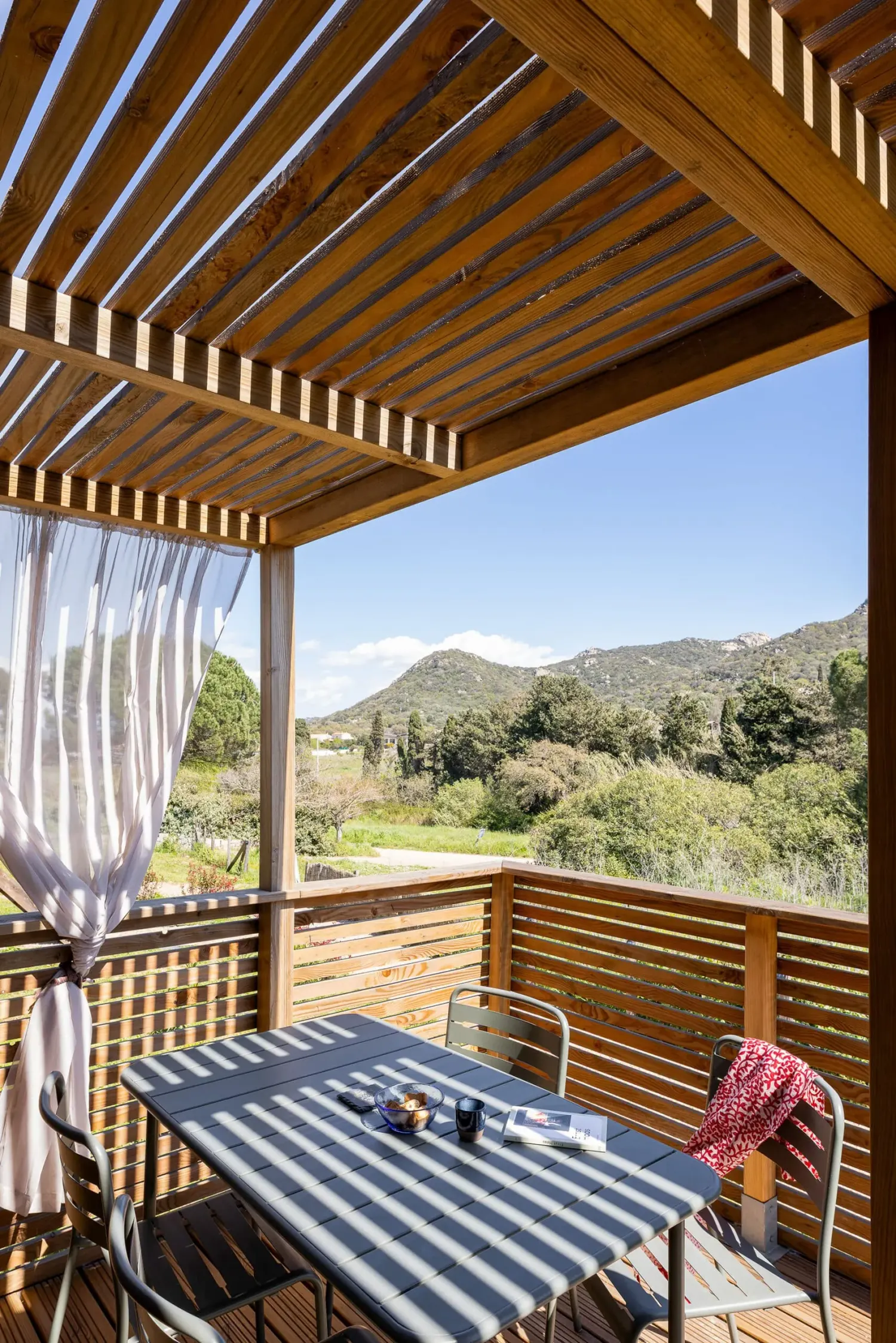 Détail de la terrasse d’un GK20 Greenkub : lames de bois horizontales, montants verticaux et garde-corps ajouré