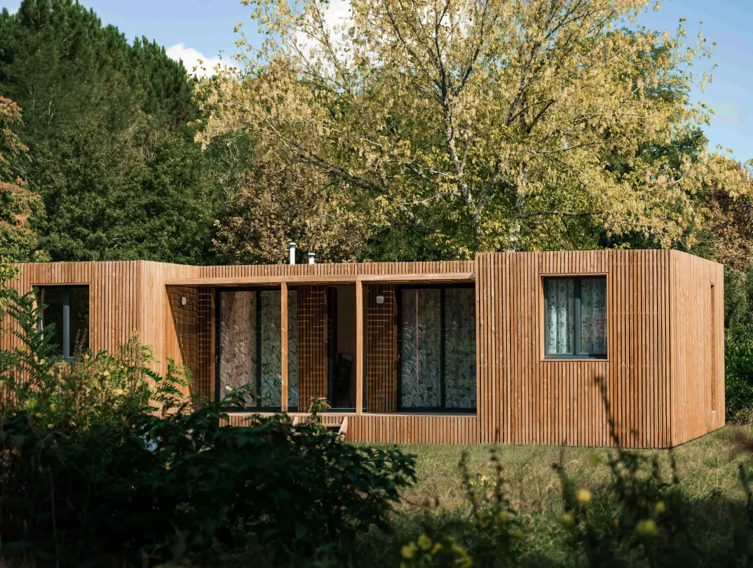 Studio de jardin de plain-pied en ossature bois, bardage à claire-voie et grandes baies vitrées, installé en lisière de bois