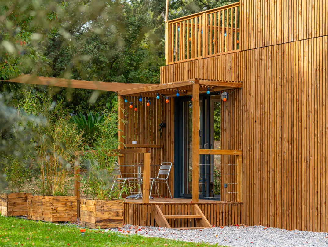 Studio de jardin tropézien avec terrasse abritée, guirlande lumineuse et garde-corps d’étage, aménagé pour la location